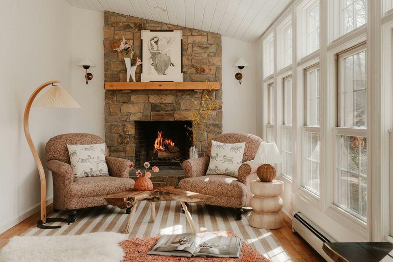 Living room with a lit stone fireplace and two armchairs